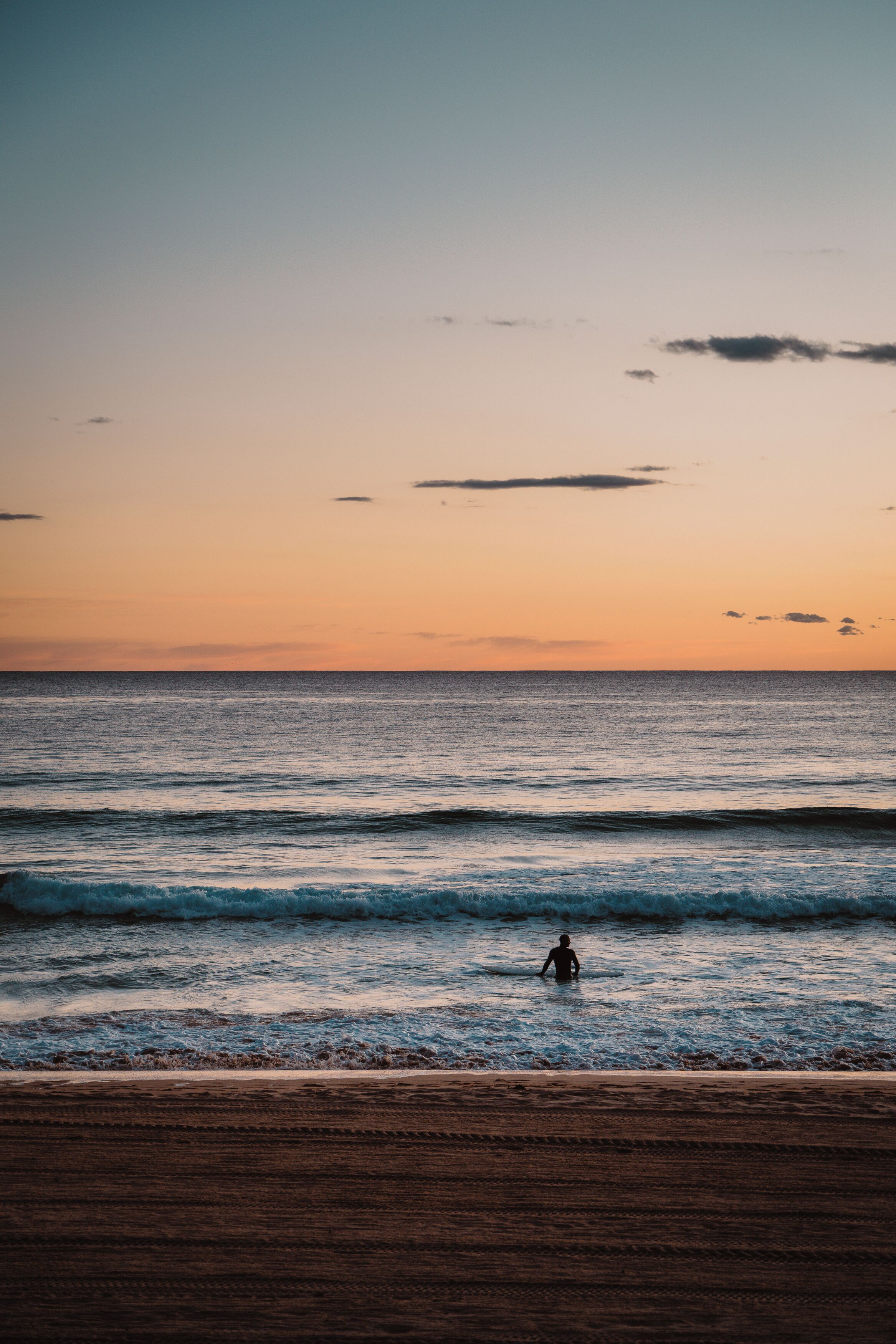 A beach scene with waves and a person in the water.