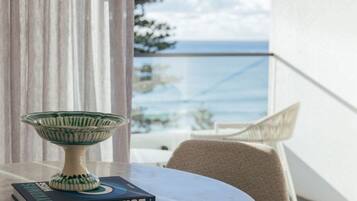 A table with a decorative bowl and a book titled 'MUSE' on a balcony with a view of the sea.