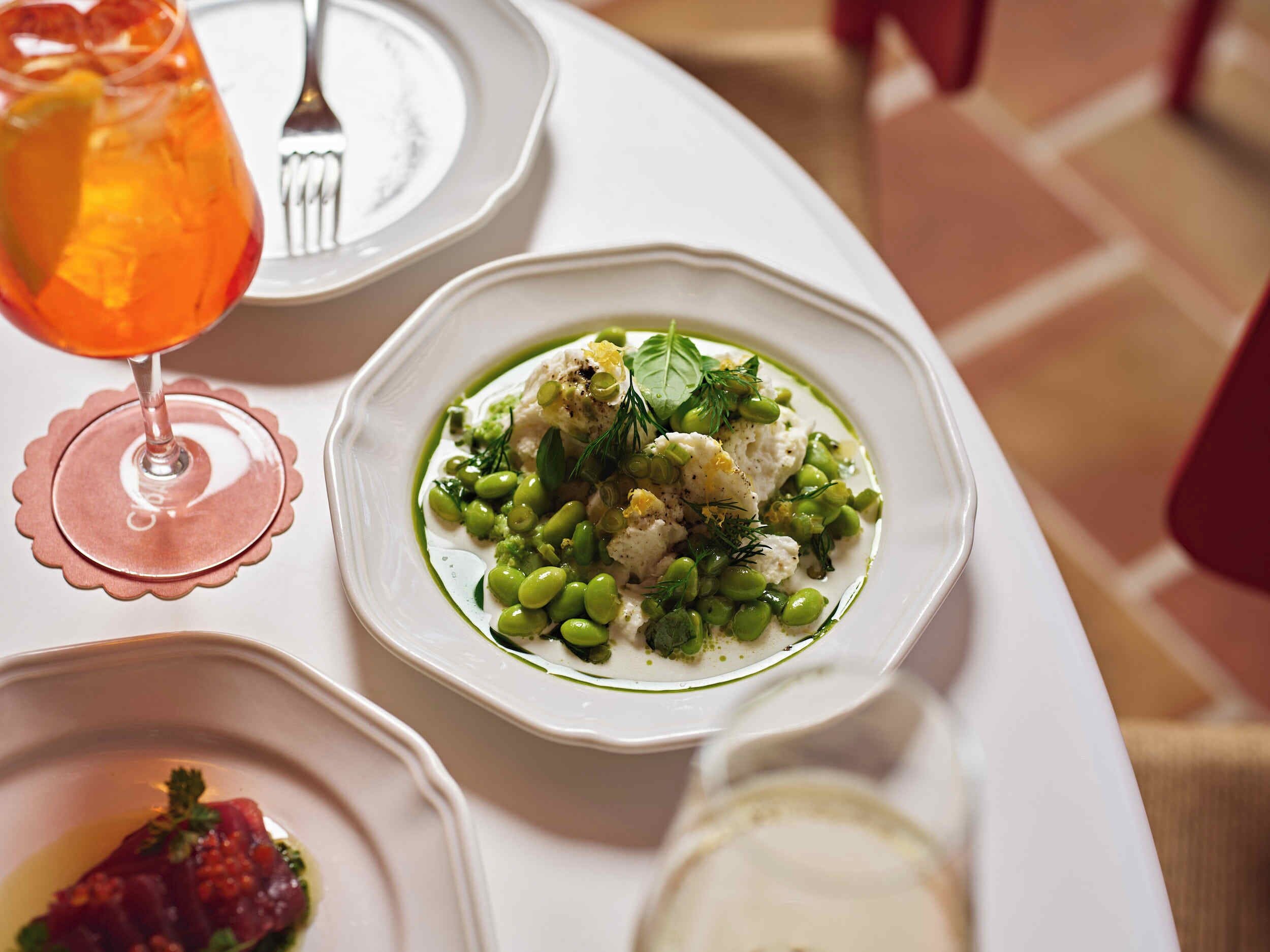 A dining table with a plate of food, a glass of drink, and a fork.