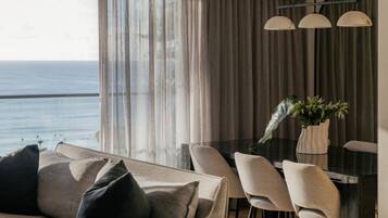 Una sala moderna con sofá, mesa de comedor, sillas y vista al mar.