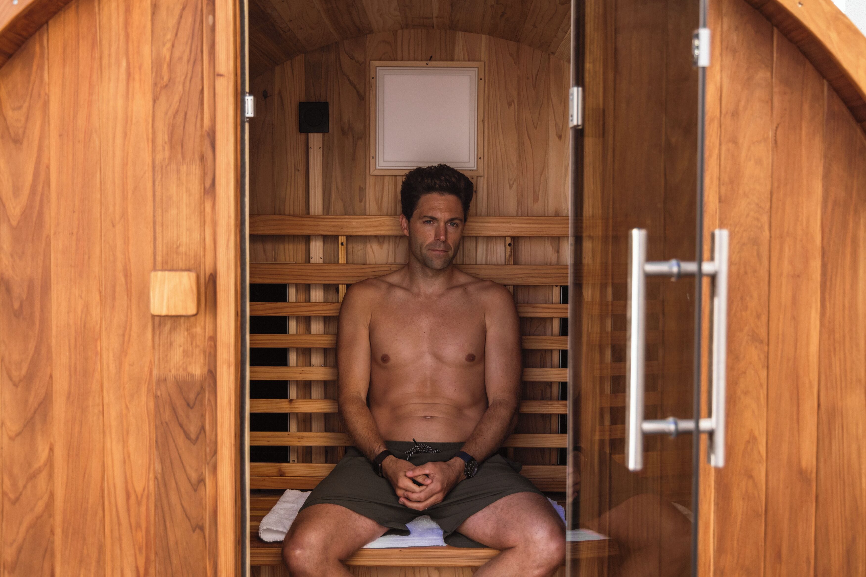Una sauna de madera con un banco y una puerta.