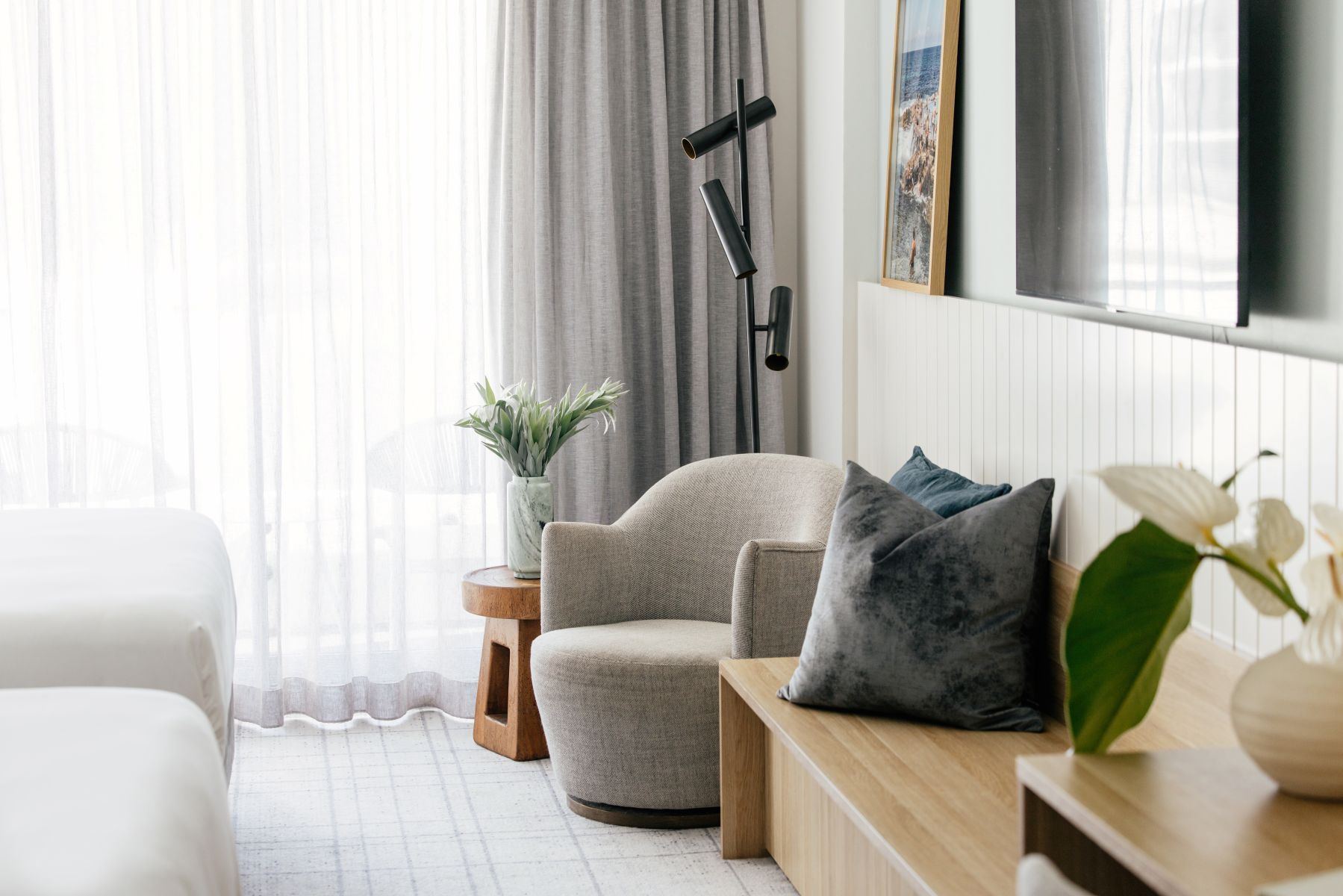 A modern living room with a sofa, a small wooden side table, and a floor lamp.