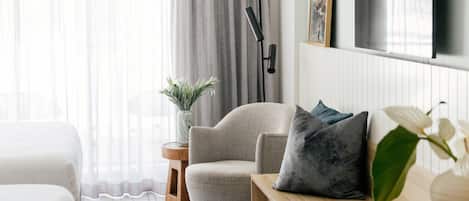 A modern living room with a sofa, a small wooden side table, and a floor lamp.