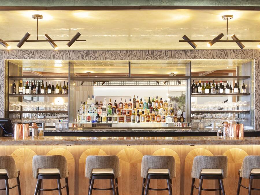A bar area with a mosaic tile floor, wooden bar counter, and multiple stools.