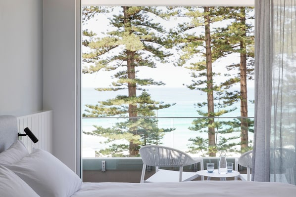 Ett hotellrum med ett stort fönster med utsikt över ett snötäckt landskap och havet.
