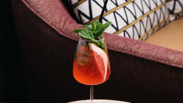 A cocktail glass with a mint garnish on a round wooden table.