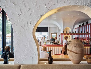 An interior with a bar area, seating, and a large vase.