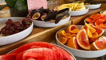 Una mesa de buffet con varias frutas y un cartel sobre abastecimiento local.