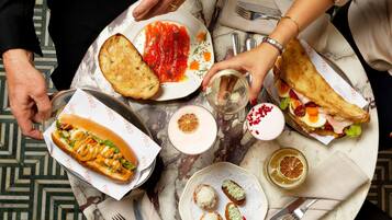 Una mesa con diferentes alimentos, incluyendo un sándwich, un perro caliente y un plato con salsa roja.