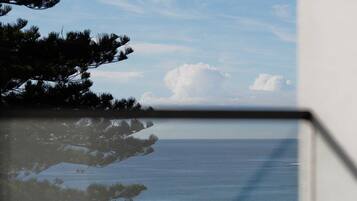 A view of the ocean through a window, with a chair in the foreground.