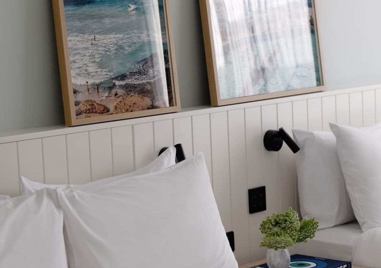 Um quarto com uma cama branca, um sofá branco e uma luminária fixada na parede.