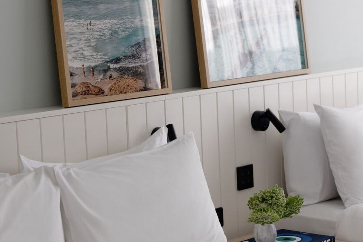 A room with a white bed, a white sofa, and a wall-mounted lamp.