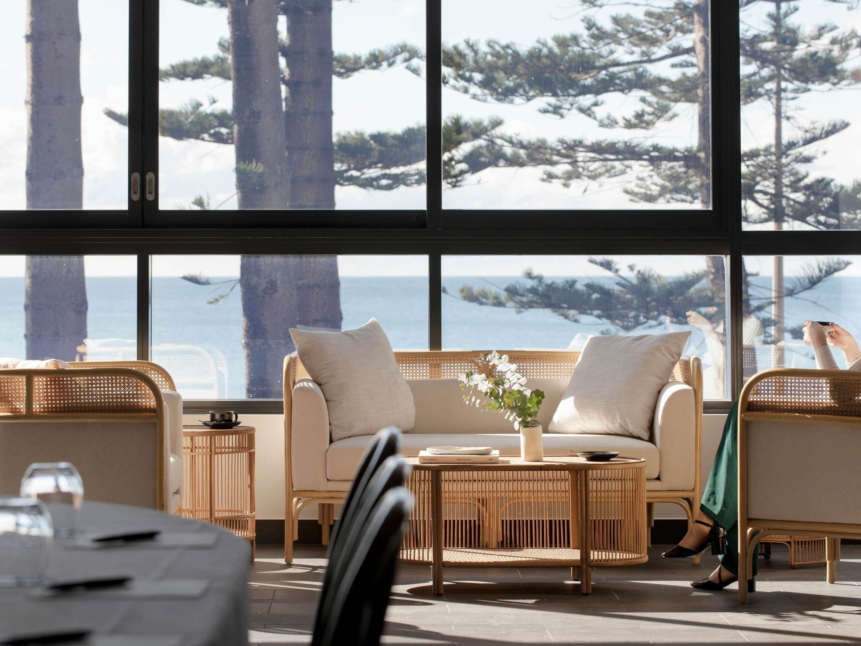 A cozy seating area with a sofa and chairs, a small table, and a view of the ocean through large windows.