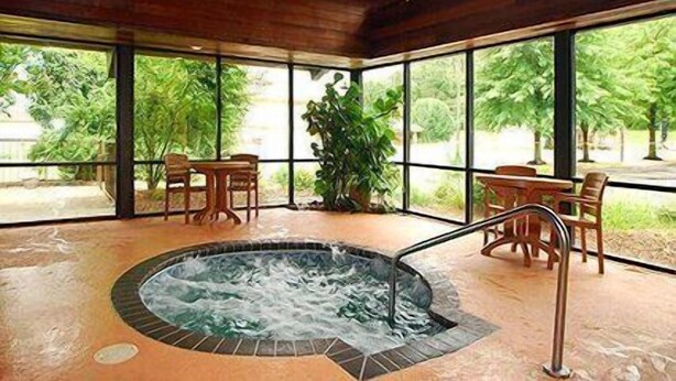 Un espace avec un bain à remous, doté d’un plafond en bois et de grandes fenêtres.