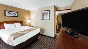 Une chambre d’hôtel dotée d’un grand lit, d’un téléviseur à écran plat et de deux œuvres d’art encadrées accrochées aux murs.