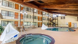 Un hôtel à plusieurs étages doté d’un espace piscine comprenant un jacuzzi et des fauteuils de détente.