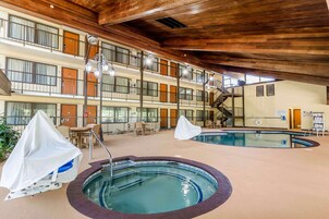 A multi-story hotel with a pool area, including a hot tub and lounge seating.