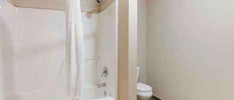Un baño con bañera, cortina de ducha y retrete.