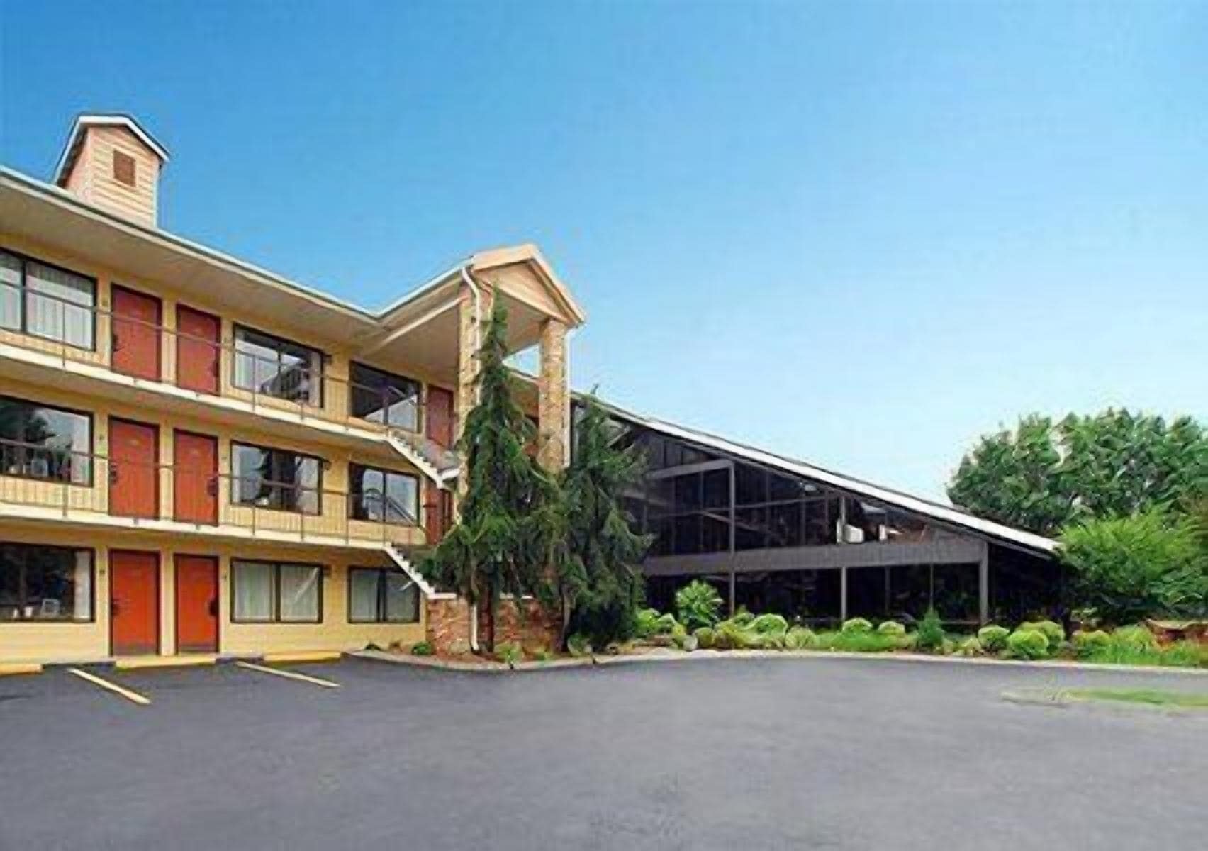 A two-story motel with a central staircase, a covered outdoor area, and a parking lot.
