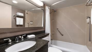 Un bagno moderno con lavabo su piano in granito, un water bianco e una vasca da bagno.