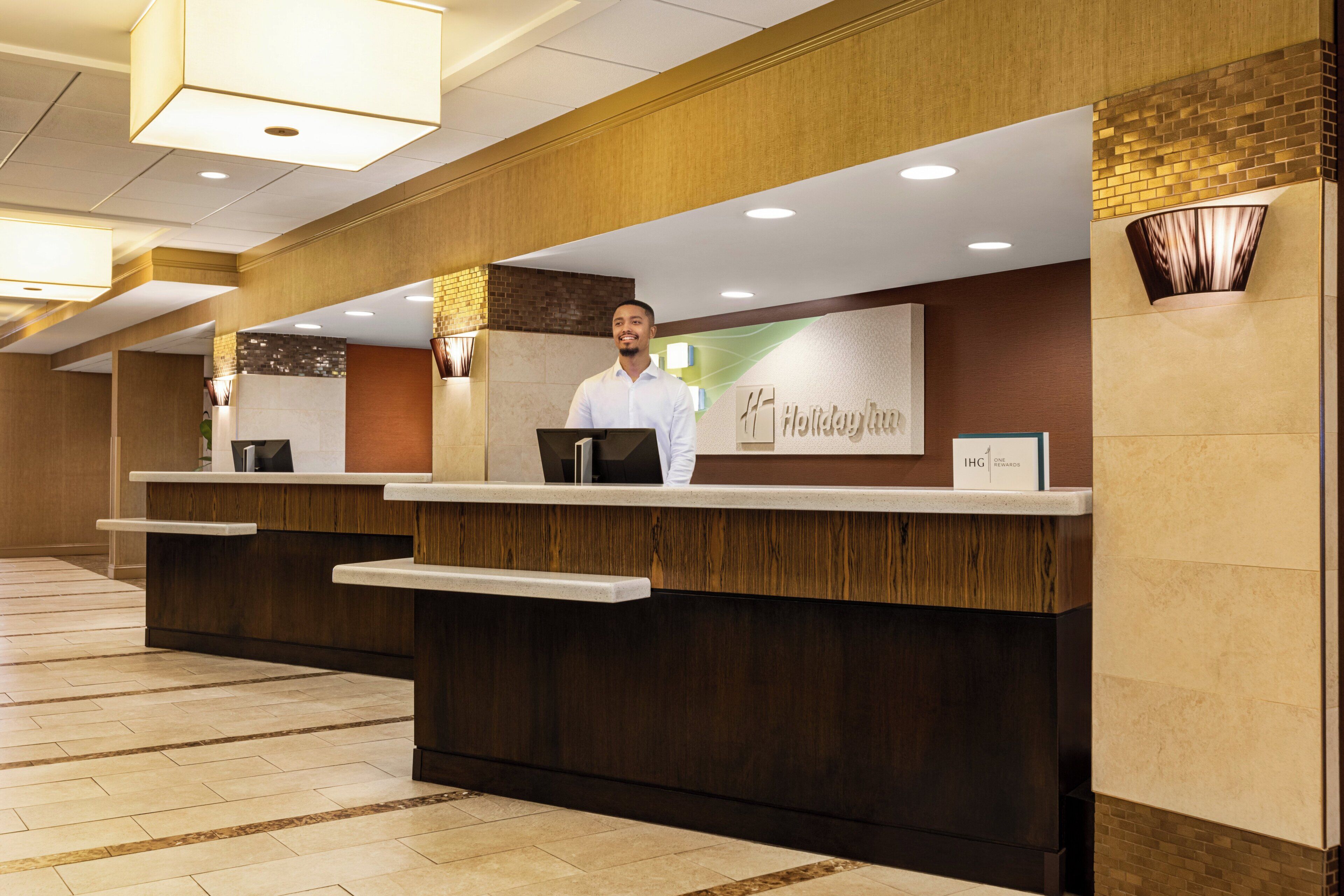 Un mostrador de recepción de hotel con diseño moderno, una pantalla digital y un cartel que indica 'Holiday Inn Express'.
