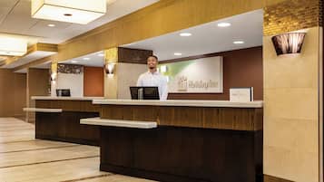 A hotel reception desk with a modern design, a digital screen, and a sign indicating 'Holiday Inn Express'.