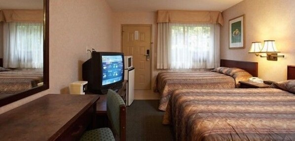 A hotel room with two beds, a television, a desk, and a lamp. - Langley Hwy Hotel (Langley)