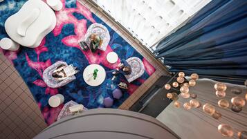 A modern interior with geometric patterned flooring, seating areas, and a ceiling with recessed lighting.