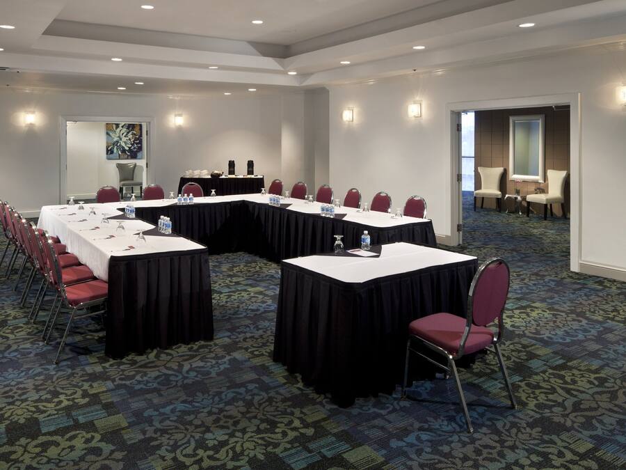 A conference room with a long table, chairs, and a carpeted floor.