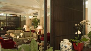A spacious lobby with a sofa, red chairs, a coffee table, and potted plants. - Dei Borgognoni Hotel (Rome)
