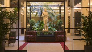 A lobby with a central statue, potted plants, and a red carpet. - Dei Borgognoni Hotel (Rome)