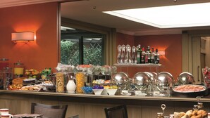A buffet setup with various food items, a selection of beverages, and dining tables with chairs. - Dei Borgognoni Hotel (Rome)