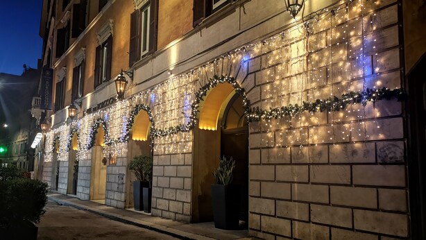 A hotel facade with multiple arched doorways, each adorned with string lights and greenery. - Dei Borgognoni Hotel (Rome)