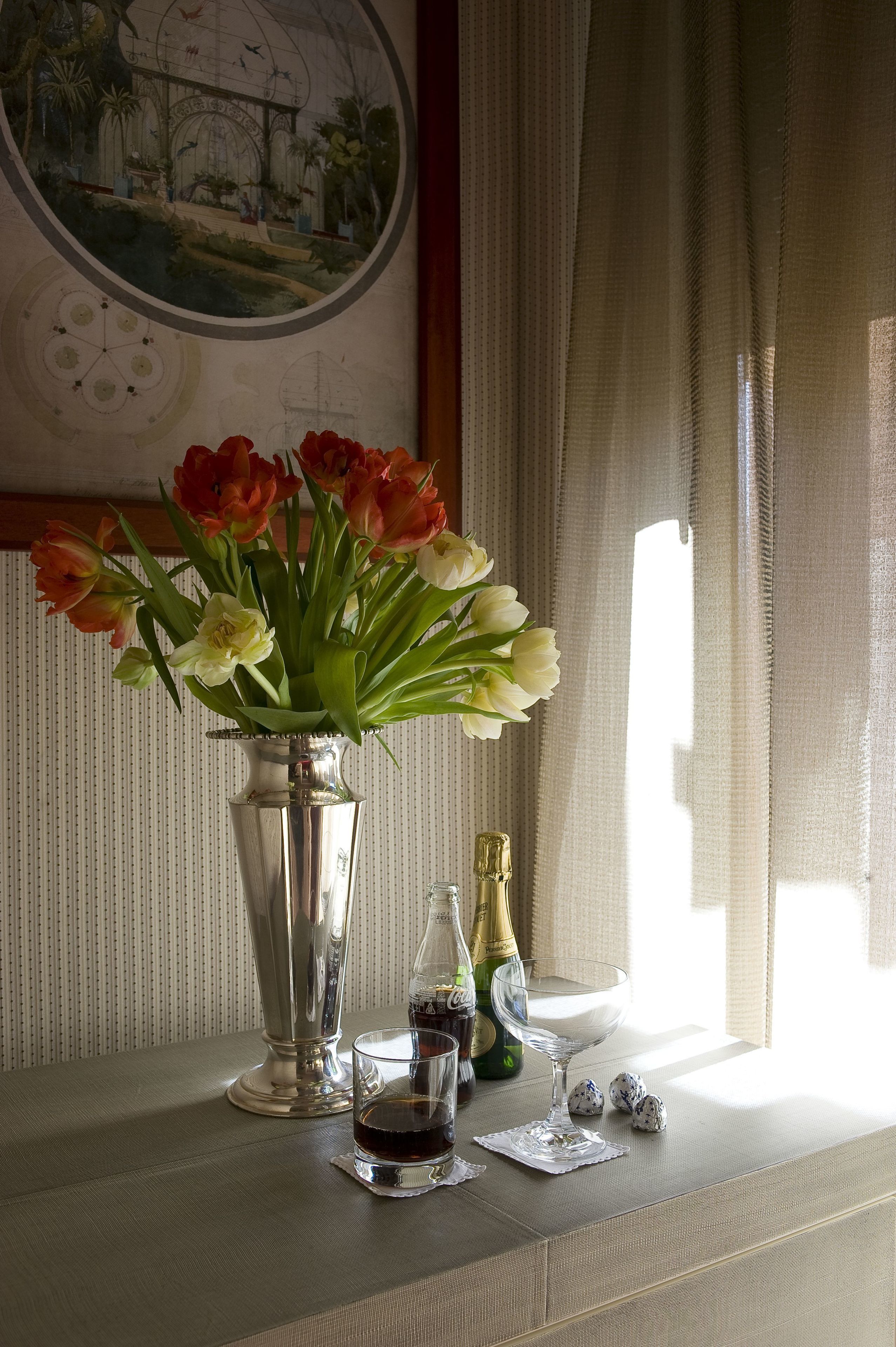 Une table avec un vase de fleurs, une bouteille de champagne et des verres.