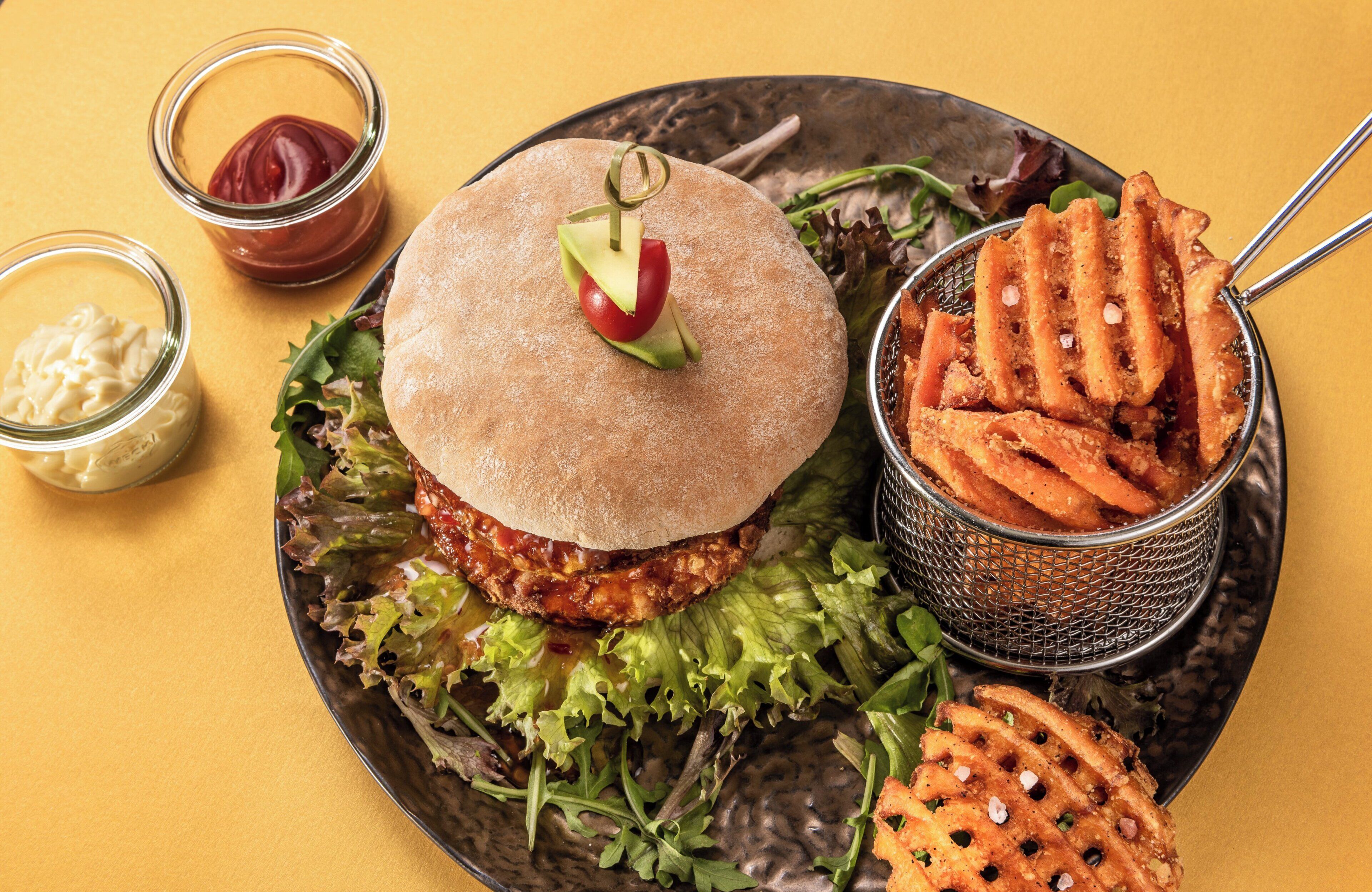 A plate with a burger, fries, and condiments.