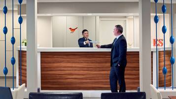 A reception area with a wooden reception desk, a red bird decoration, and blue hanging ornaments.