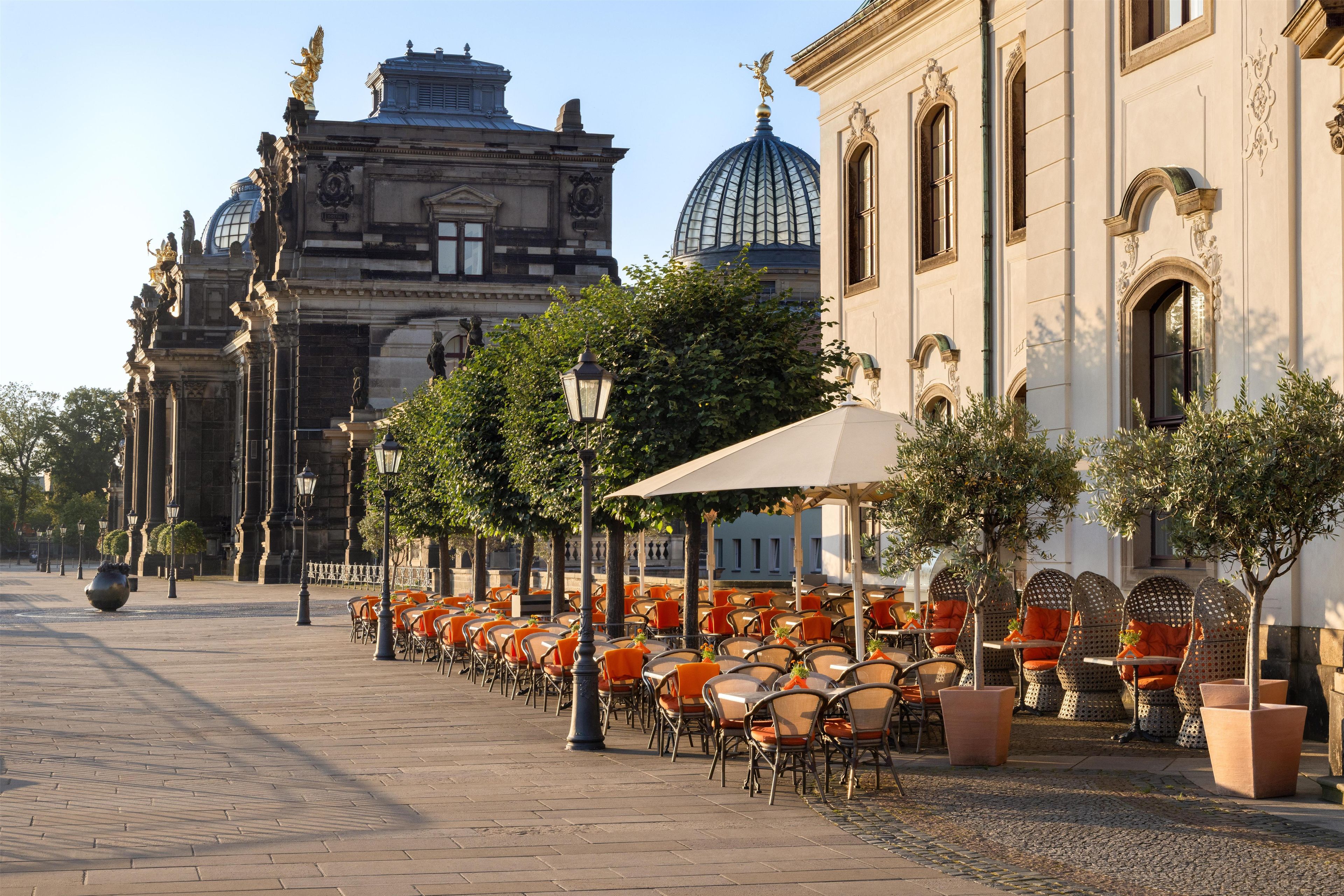 A paved street with outdoor seating, a historic building with ornate architecture, and a clear sky.