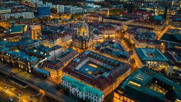An aerial view of a cityscape at dusk with illuminated buildings and streets.