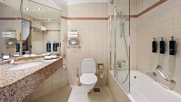 A modern bathroom with a granite countertop, a toilet, a glass-enclosed shower, and a large mirror.