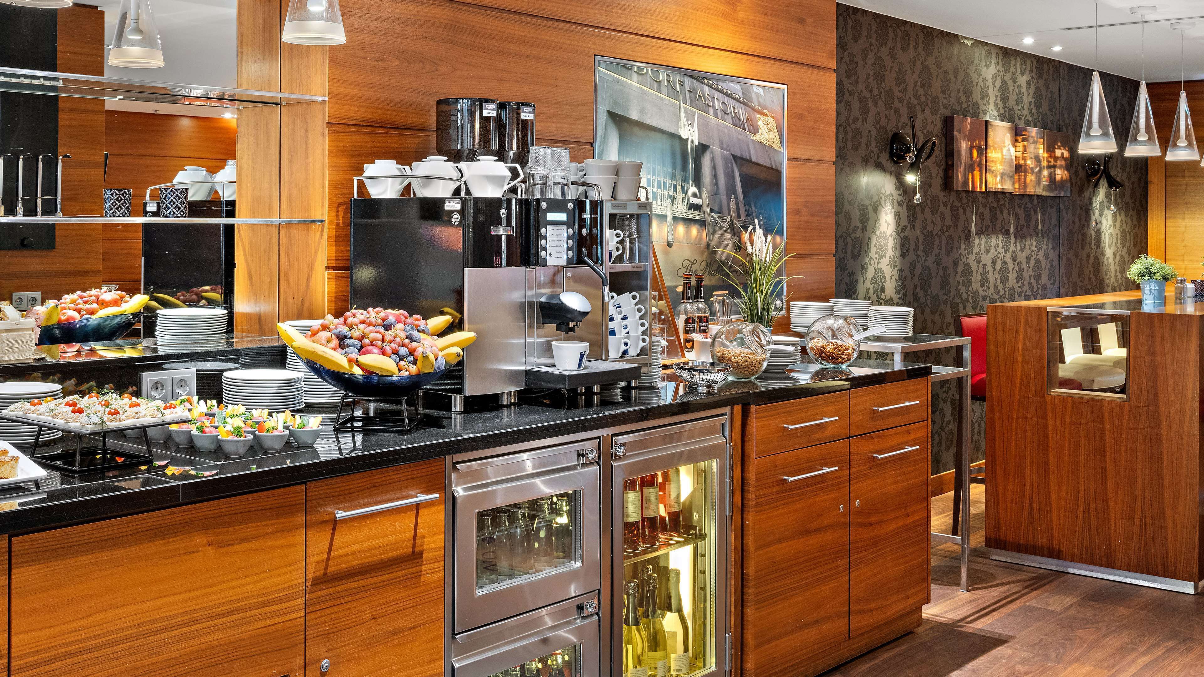 A modern kitchen with a coffee station, fruit bowl, wine refrigerator, and wooden cabinets.
