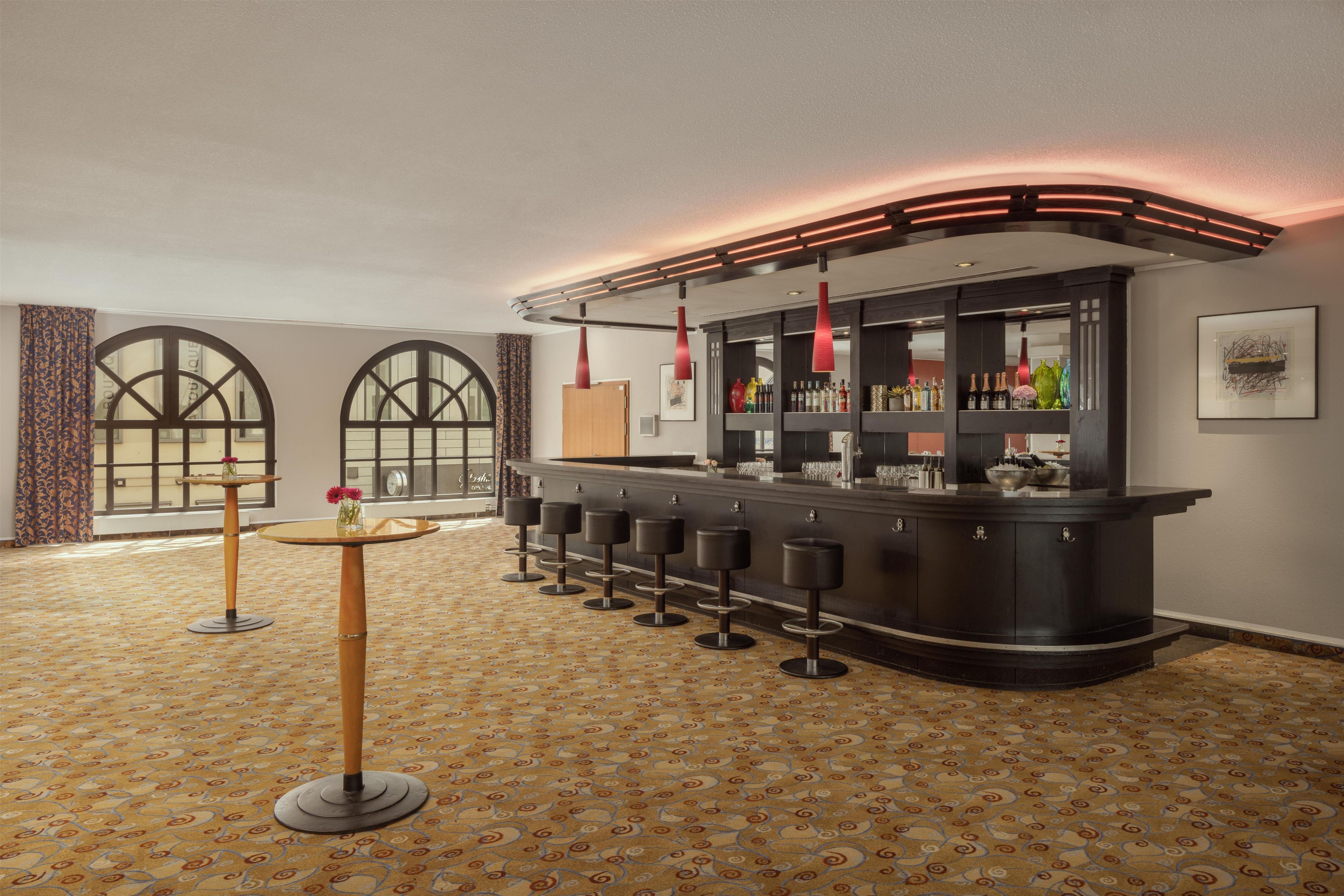 A bar area with a curved counter, multiple stools, and a patterned carpet.