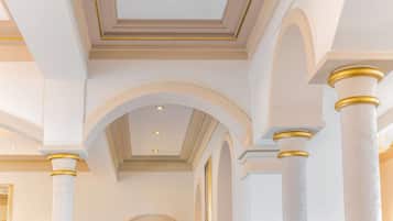 A grand hallway with white columns and arches, a recessed ceiling, and a central light fixture.