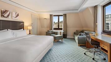 Habitación de hotel con una cama grande, un escritorio, una silla y una mesita.
