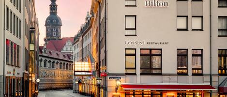 A street view with a hotel and restaurant named 'Rossini' and 'Hilton' with outdoor seating.