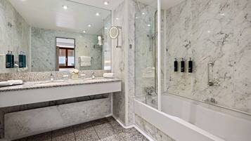 A modern bathroom with a marble vanity, a large mirror, and a glass-enclosed shower.