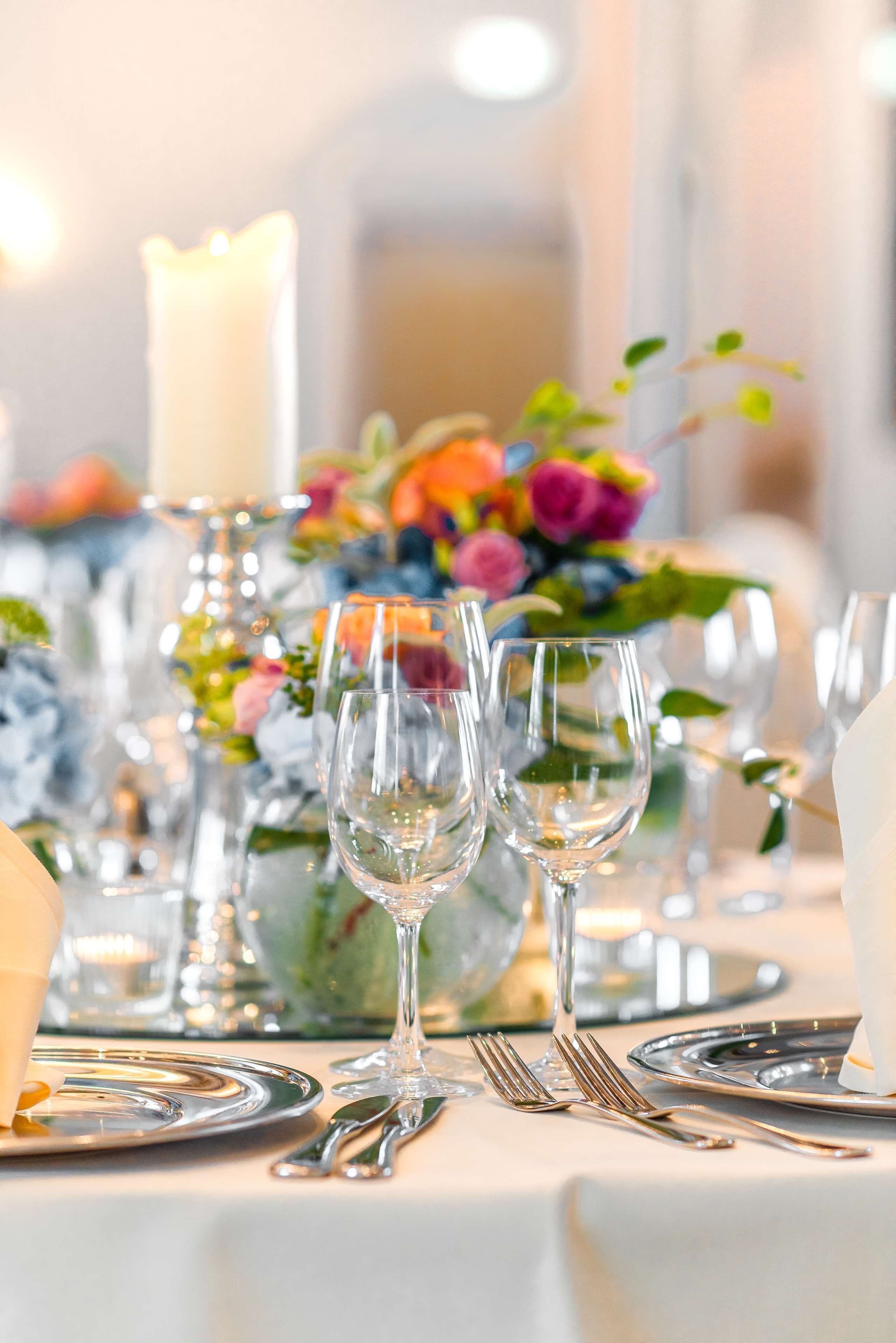 A table set for dining with clear glassware, silverware, and a candle centerpiece.