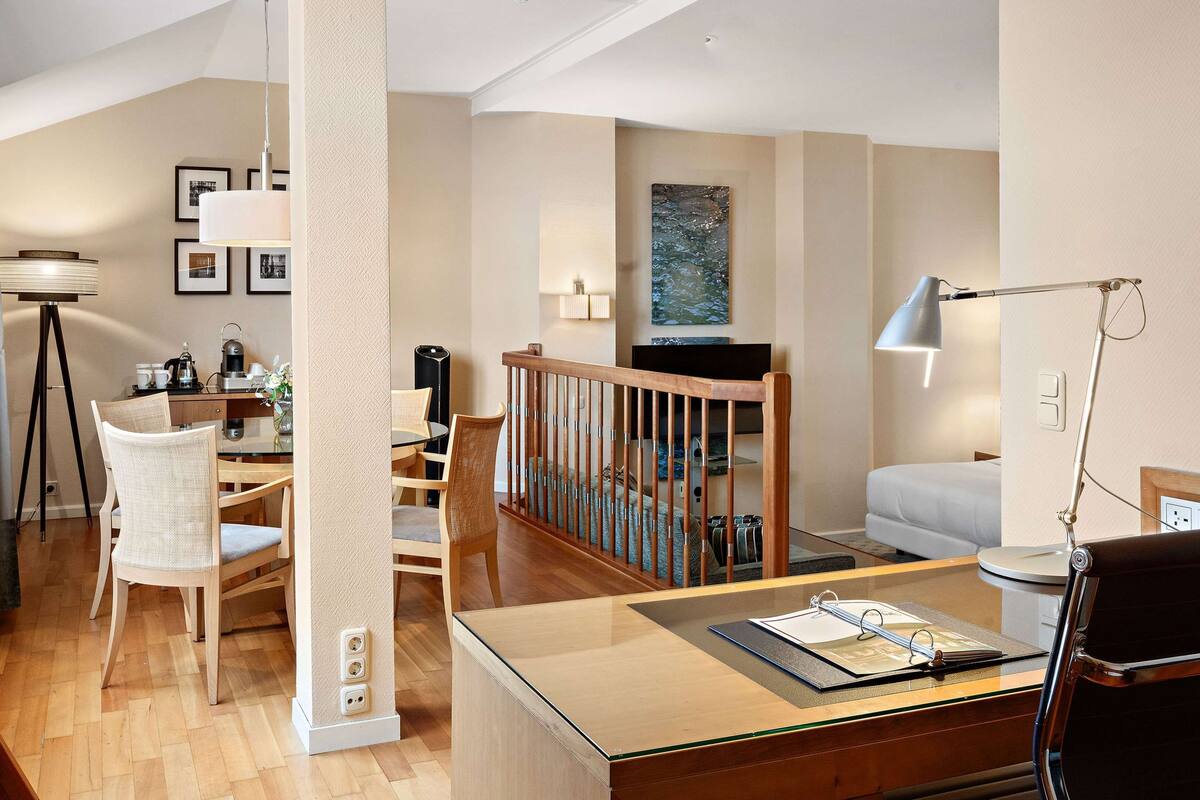 A modern living room with a dining area, wooden furniture, and a staircase.