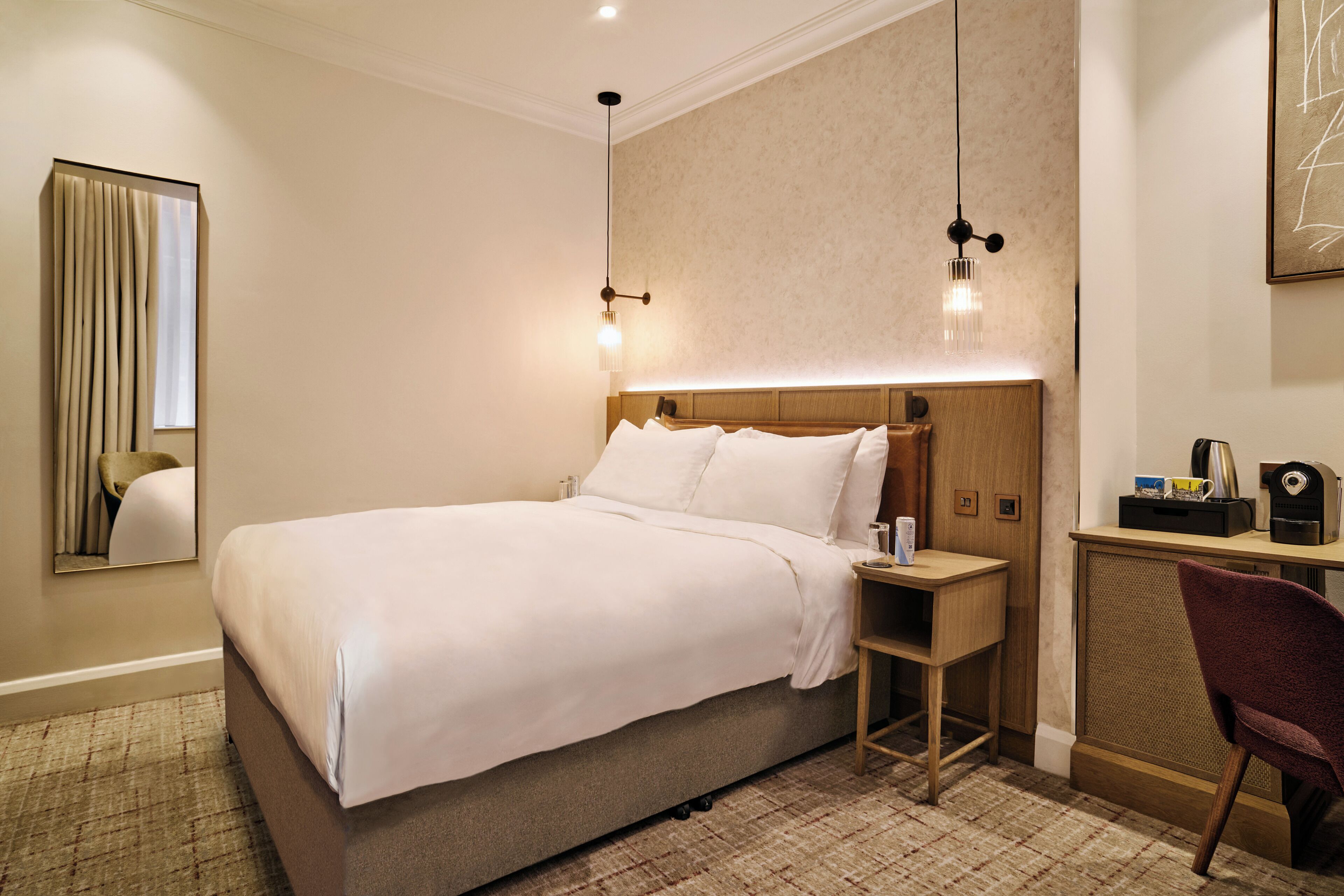 Una habitación de hotel con una cama grande, mesitas de noche, un escritorio y una silla.