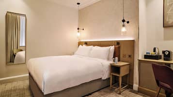 Una habitación de hotel con una cama grande, mesitas de noche, un escritorio y una silla.