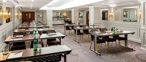 A conference room with multiple tables, chairs, and a carpeted floor.